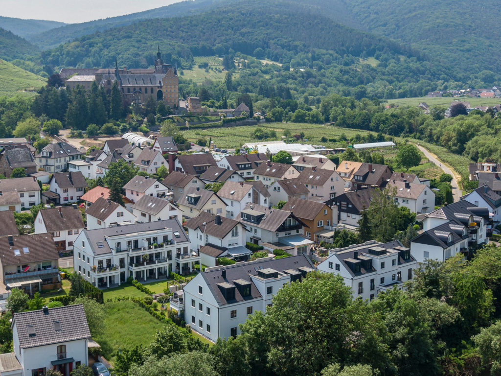 Drohnenaufnahme einer modernen Wohnsiedlung mit Burg und umliegender Landschaft im Hintergrund - professionelle Architekturfotografie