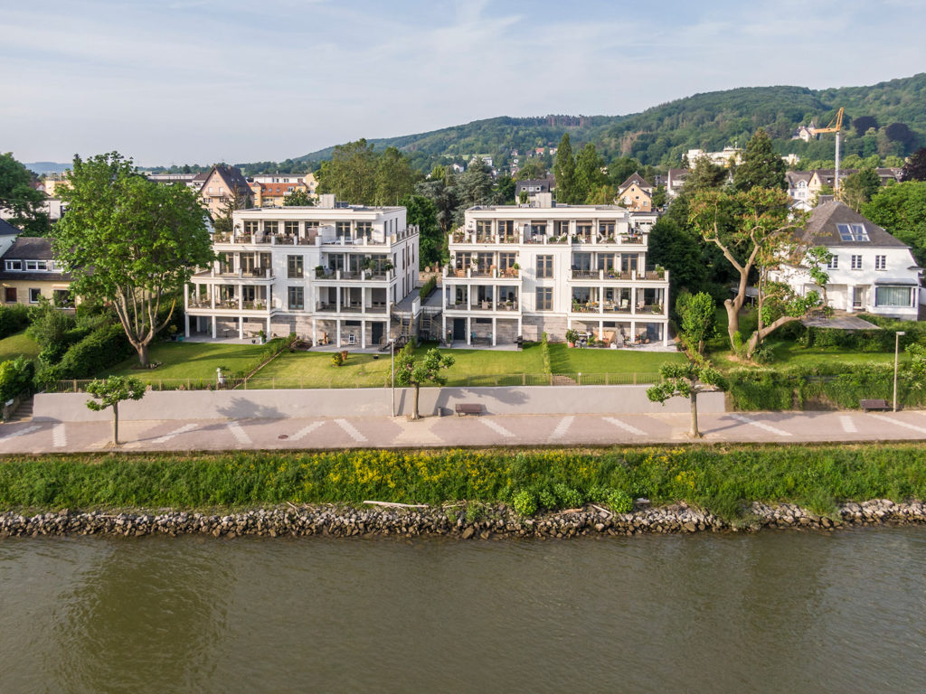 Drohnenbild moderner Mehrfamilienhäuser mit Balkonen direkt am Rheinufer - professionelle Architekturfotografie